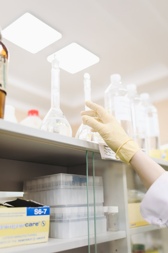 Scientist's gloved hand reaching for a beaker in a laboratory setting, showcasing research precision.